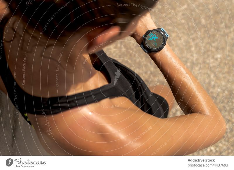 Crop-Sportlerin überprüft Smartwatch beim Training Fitness Tracker intelligente Uhr prüfen Läufer Puls Schweiß Armband Frau Gesundheit Athlet Armbanduhr tragbar