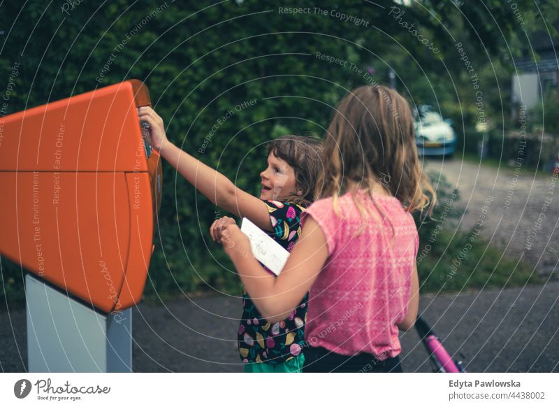 Kinder werfen eine Postkarte in den Briefkasten, Niederlande Beitrag Buchung Absendebrief Freundschaft Zusammensein Urlaub Abenteuer Sommerzeit Tag genießend