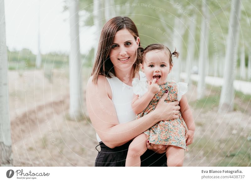 Porträt der schönen Mutter hält Baby Mädchen in Bäumen Weg. Familie, Spaß und Natur Konzept Wald Glück Kindheit Lächeln laufen Kaukasier Spanien Kleid