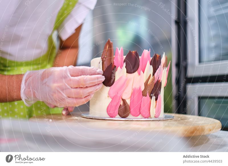 Konditor in Handschuhen beim Verzieren von Kuchen mit bunter Schokolade Frau Dessert lecker Gebäck Konditorei Stil dekorieren süß Konfekt Koch geschmackvoll