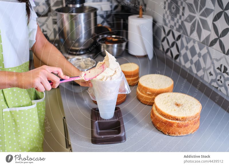Koch, der bei der Zubereitung von Kuchen in der Küche Sahne in einen Spritzbeutel gibt Frau Backwarenbeutel setzen Gebäck Dessert Schürze Lebensmittel süß