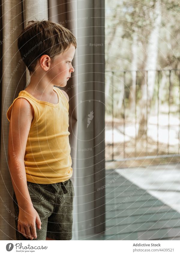 Junge steht am Fenster eines Hauses Kind nachdenklich besinnlich wenig ruhig Windstille Kindheit heimwärts friedlich bezaubernd Harmonie nachdenken Gelassenheit