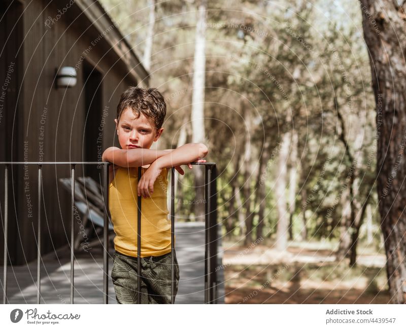 Kind steht auf der Terrasse eines Hauses im Wald Junge Veranda Erholung Sommer friedlich ruhig Natur hölzern Wälder Waldgebiet Sommerzeit sonnig Sonnenlicht