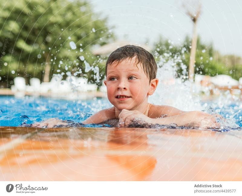 Fröhlicher Junge im Schwimmbad im Sommer Kind schwimmen Pool Beckenrand heiter Spaß haben Wasser nasses Haar Freude Lächeln Wochenende Glück genießen Vergnügen