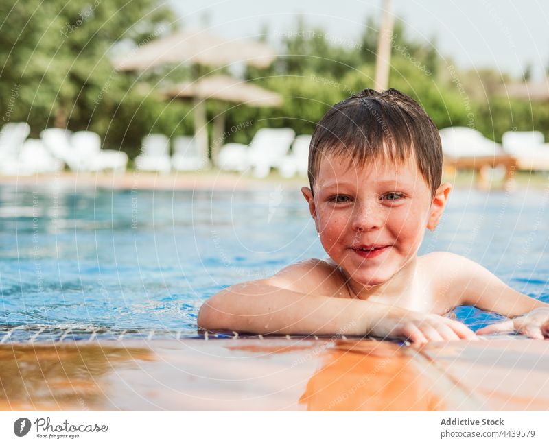 Fröhlicher Junge im Schwimmbad im Sommer Kind schwimmen Pool Beckenrand heiter Spaß haben Wasser nasses Haar Freude Lächeln Wochenende Glück genießen Vergnügen
