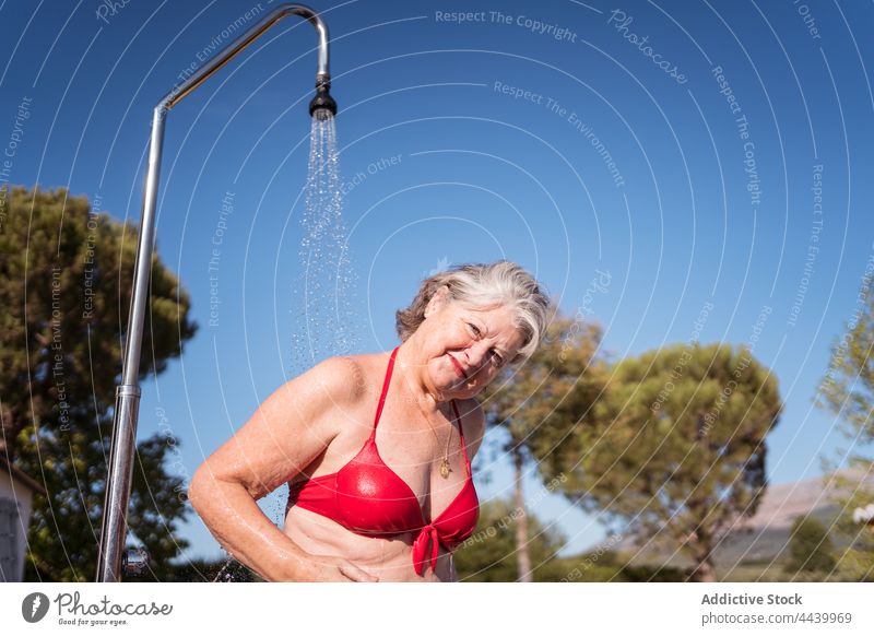 Lächelnde Frau steht unter der Dusche am Pool platschen Wasser sich[Akk] entspannen genießen Waschen Beckenrand Sauberkeit durchsichtig Tropfen heiter Vergnügen