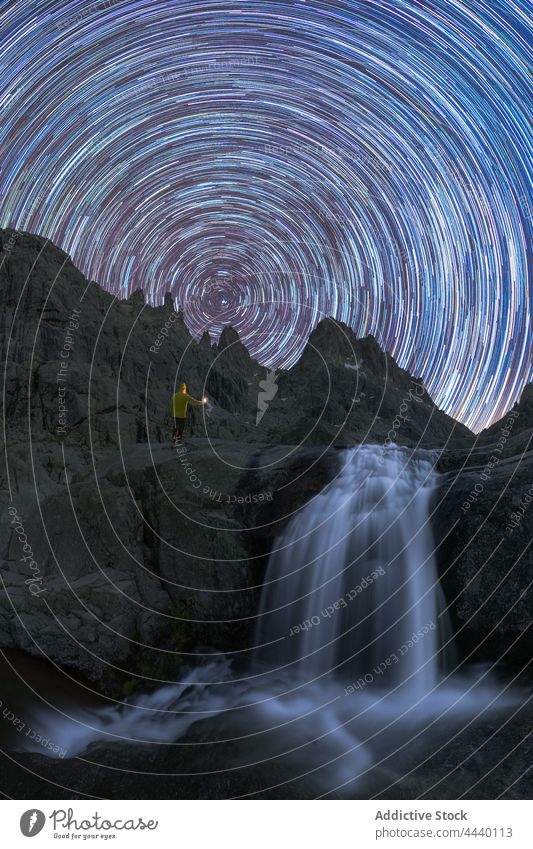 Tourist betrachtet Wasserfall auf Berg unter Sternenschweif bei Nacht Reisender Kaskade Sternenpfad Berge u. Gebirge Natur Hochland Bewegung Geschwindigkeit