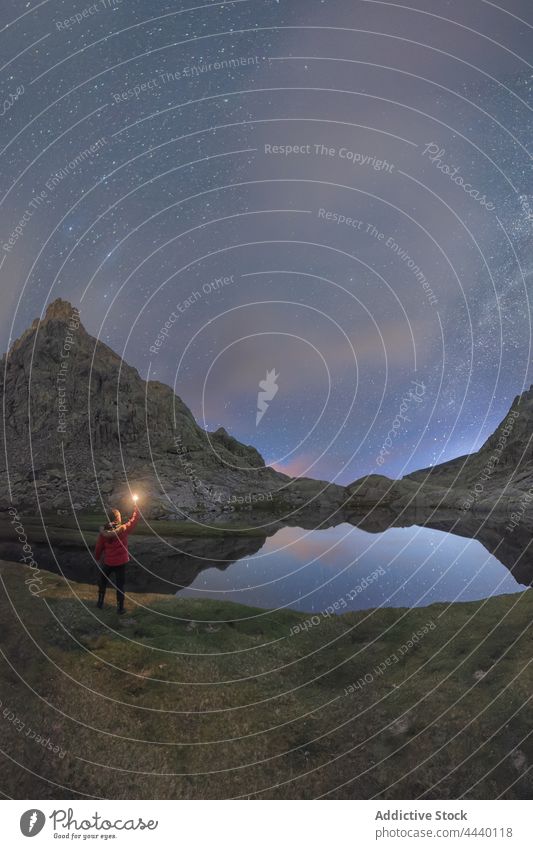 Anonymer Reisender bei der Betrachtung von Bergen und Teich unter der Milchstraße Berge u. Gebirge Milchstrasse Natur Hochland Landschaft Astronomie Mann Nacht