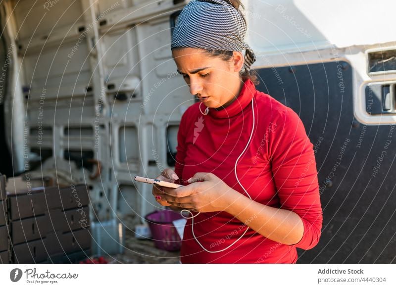 Seriöser Landwirt, der während der Arbeit eine SMS auf seinem Smartphone schreibt Frau benutzend zuschauen Nachricht ernst Suche Browsen Job Bauernhof Apparatur