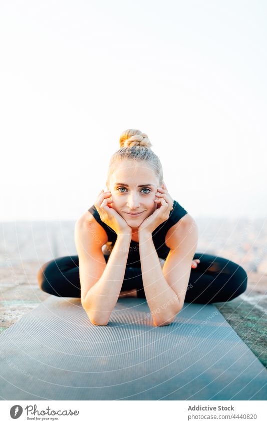 Lächelnde Frau macht halben Lotus und stützt sich auf Hände halber Lotus positiv Sonnenuntergang Wiederherstellung Asana Yoga Wellness üben sportlich