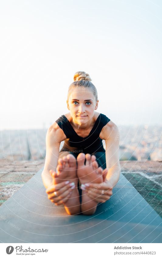 Lächelnde barfuß Frau macht sitzende Vorwärtsbeuge Yoga Sonnenuntergang Körperhaltung Gesundheit üben Dehnung Wohlbefinden passen paschimottanasana