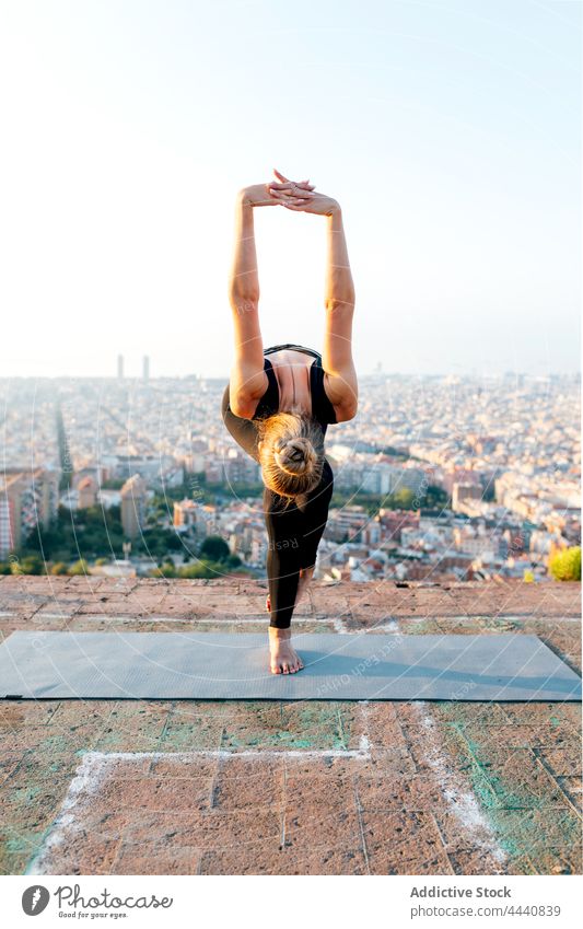 Anonyme Frau in Adlerpose auf Yogamatte stehend Adler-Pose Vorwärtsbeuge Arme hochgezogen Gleichgewicht Dehnung beweglich Wellness urban üben