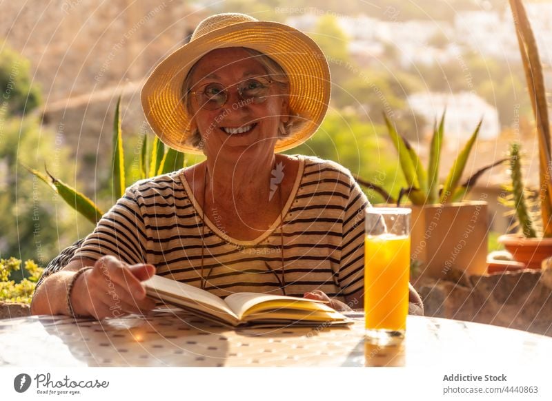 Alte Frau liest ein Buch in einem Cafe Senior lesen Hobby Literatur Zeitvertreib Interesse Freizeit Café älter alt Roman gealtert graues Haar Getränk Tisch