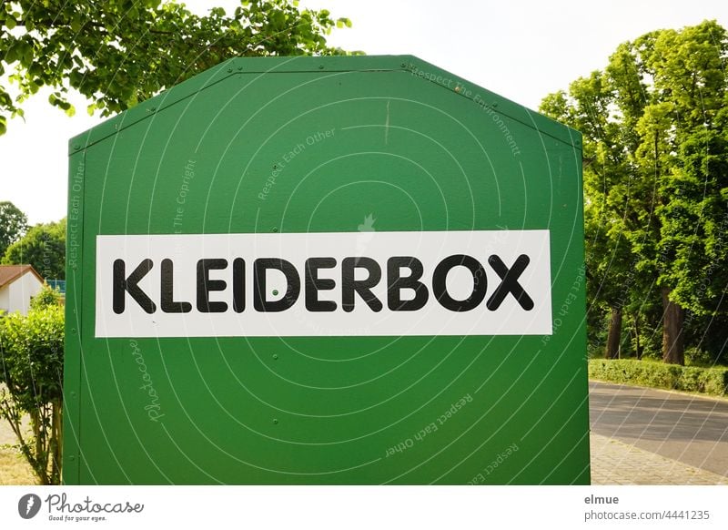 an einer Straße stehender grüner Metallbehälter mit der Aufschrift KLEIDERBOX / Textilrecycling Kleiderbox Altkleidersammlung Kiloware gemeinnützig Container