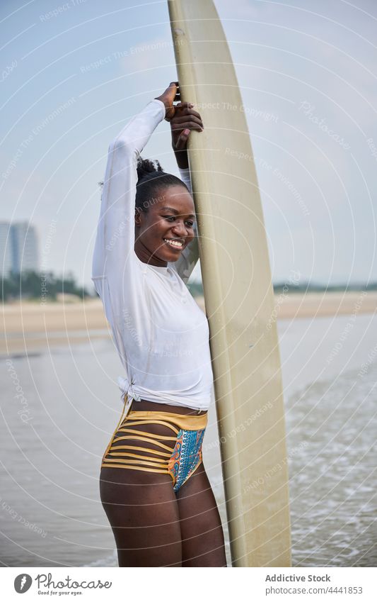 Schwarzer Surfer mit Longboard, der das Meer vom Strand aus betrachtet Sport Surfen nachdenken Natur Blauer Himmel Frau Sportlerin schwarz ethnisch