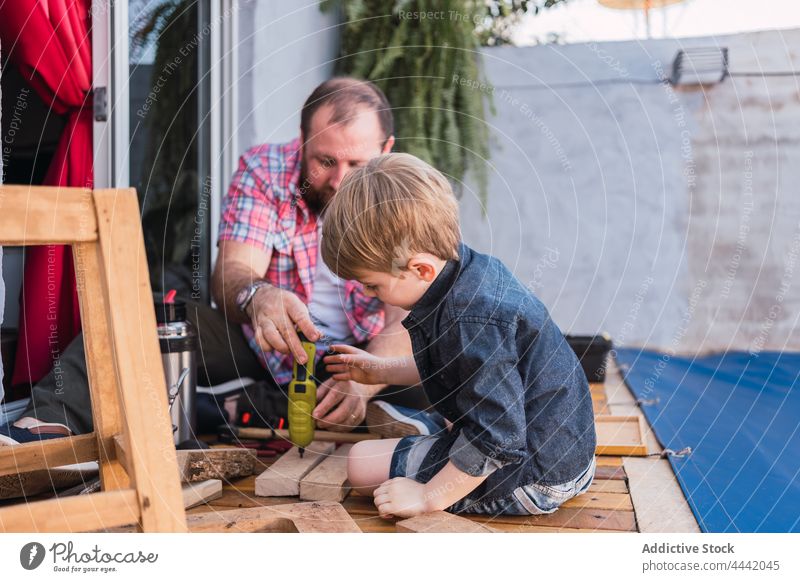 Vater mit Sohn misst Holzteile mit Maßband messen Klebeband Holzarbeiten handgefertigt Spielfigur achtsam präzise Kindheit Mann Hipster Werkzeug Papa