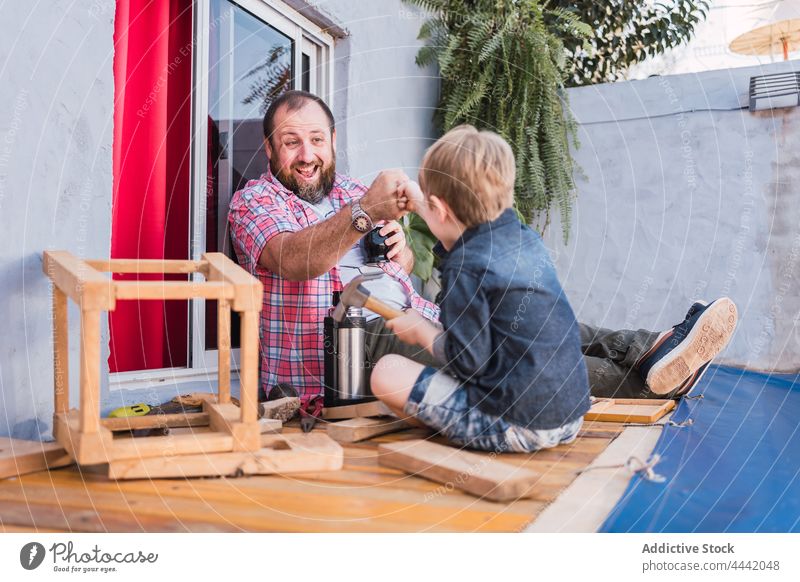 Lächelnder Vater mit Sohn, der sich bei der Holzarbeit die Fäuste stößt Papa Fistbump einigen Holzarbeiten diy Handwerk Zeit verbringen Kindheit Mann