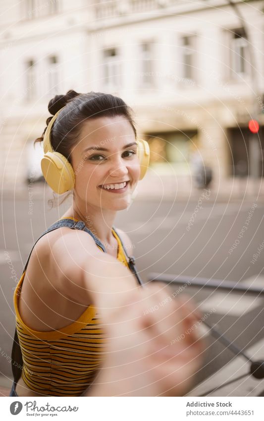 Fröhliche Frau mit Kopfhörern streckt die Hand in die Kamera Musik zuhören Drahtlos positiv Hobby genießen sorgenfrei Gesang Apparatur Freude zufrieden Audio