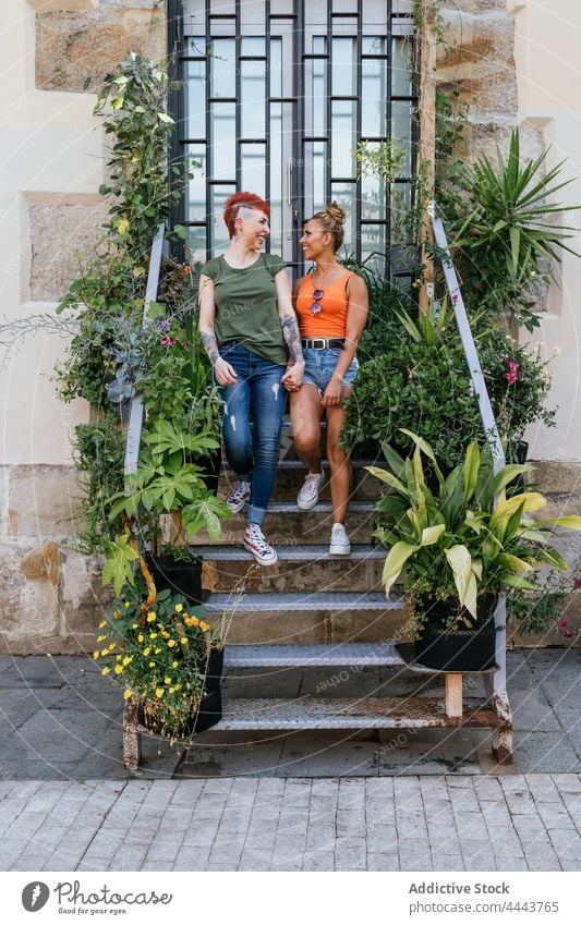 Lächelndes lesbisches Paar, das sich auf einer Treppe stehend unterhält und die Hände hält sprechen Partnerschaft Inhalt Zeit verbringen cool lgbt Frauen ruhen