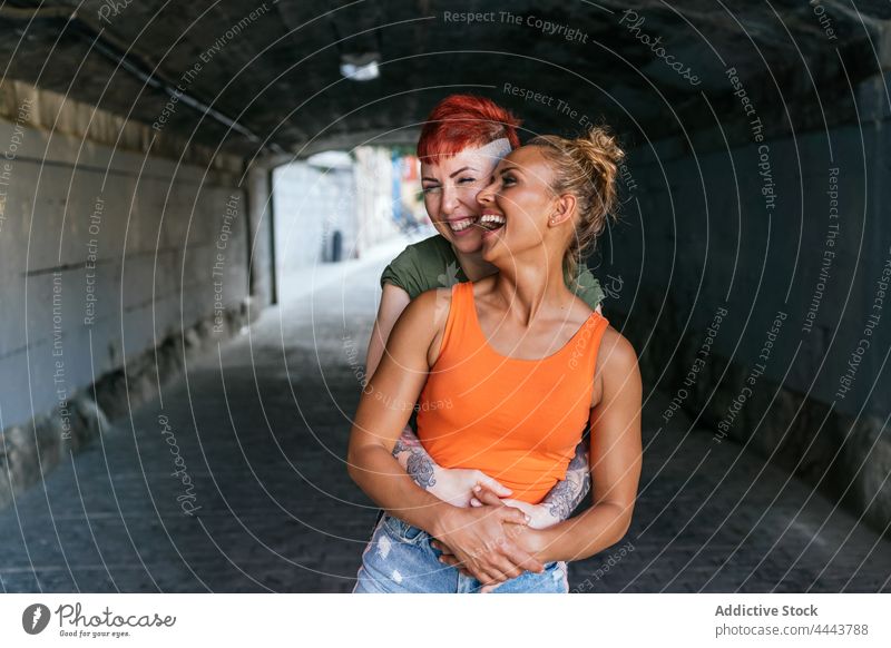 Glückliches lesbisches Paar, das sich in einem städtischen Tunnel umarmt Umarmen Lachen Partnerschaft Liebe Romantik interagieren Stollen cool Frauen Freundin