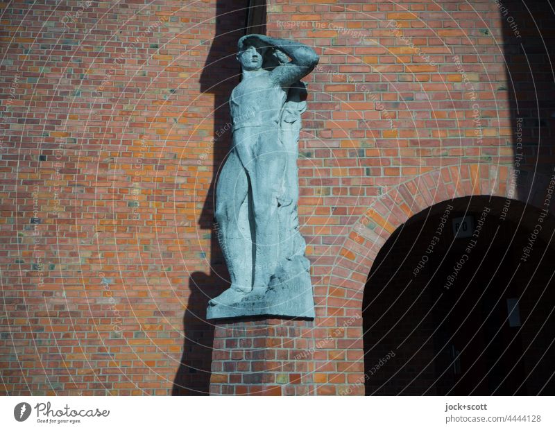 Statur vor der Fassade mit Klinker Statue Wand alt Sonnenlicht Sockel Schatten Reinickendorf Berlin Rundbogen Kunst am Bau männlich verwittert Körperhaltung
