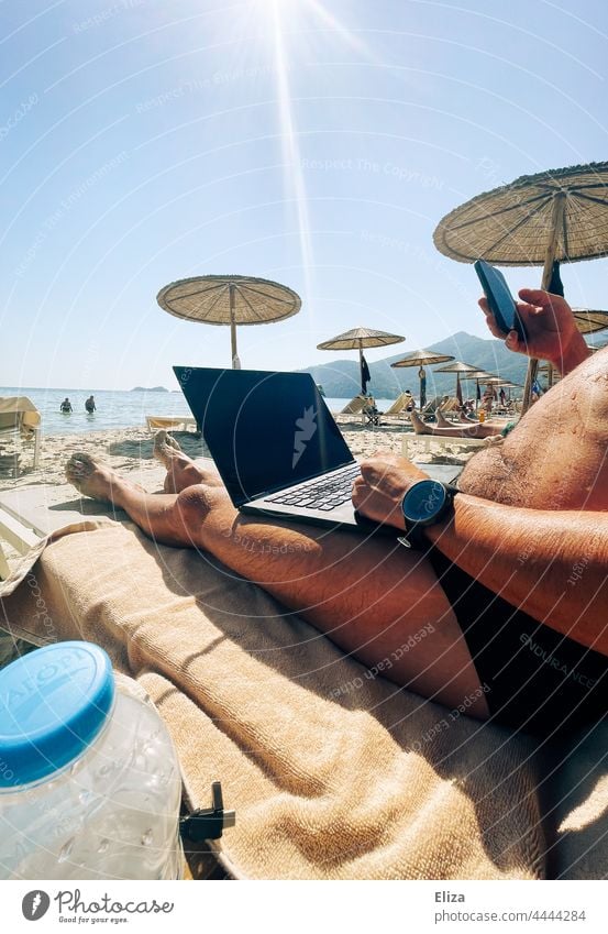 Mann arbeitet im Urlaub am Strand am seinem Laptop arbeiten Digitaler Nomade Arbeitsplatz Sonne Workaholic Business Computer Notebook digital Homeoffice Handy
