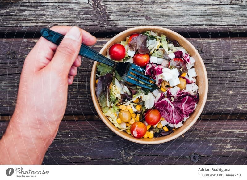 Salat mit Tomaten, Mais und Käse von Hand gegessen. Umweltfreundliche Kartonverpackung Umweltschutz Essen Salatbeilage umweltfreundlich Gemüse Versand Öko Paket