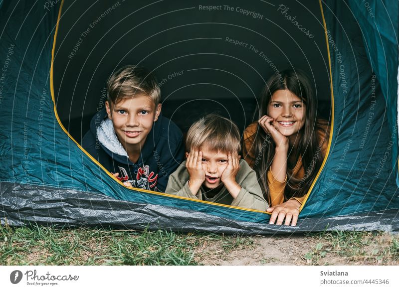 Lächelnde Kinder liegen zusammen in einem Zelt auf einem Campingplatz. Familienzeit, Familienurlaub, Wandern am Wochenende Zusammensein Mädchen Junge Lifestyle
