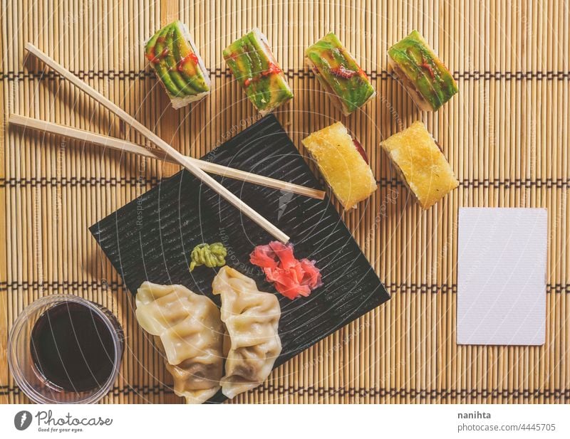 Fushion-Essen mit modernen Kalifornien-Rollen und Gyoza Sushi Japanisch Lebensmittel Fusion Avocado lecker Soja Sojasauce Bambus Sushi-Matte Unterlage Reis