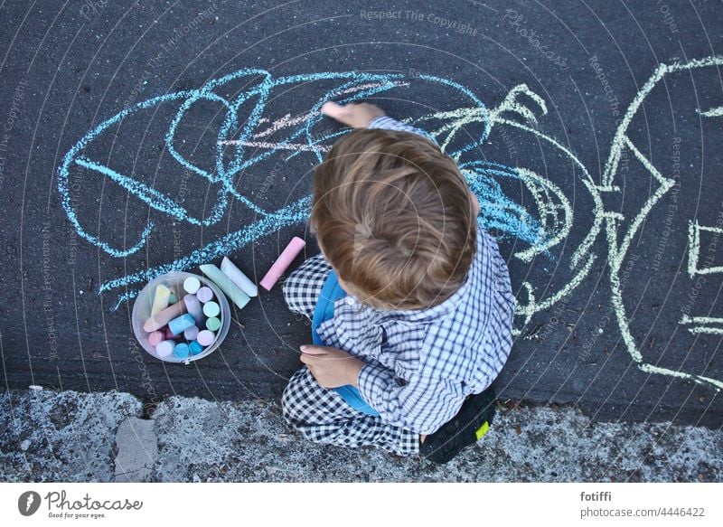 Kind malt mit Kreide auf Straße Kreidezeichnung malen Kinderspiel Strassenmalerei Kunst Kreativität Kindheit Spielen zeichnen Straßenkreide Zeichnung Teer bunt