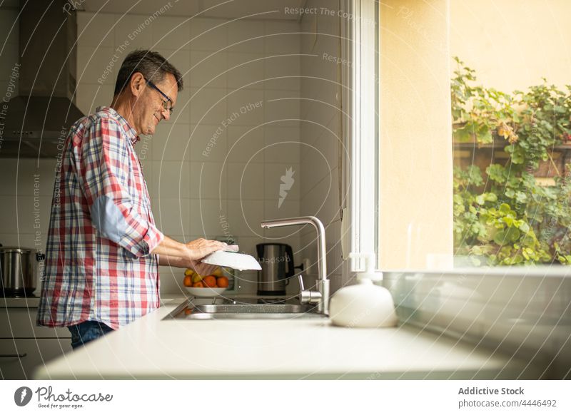 Mann wäscht Geschirr in der Küche zu Hause Waschen Speise Haushalt reinigen Sauberkeit Fenster Single stehen Freizeit Seife Ehemann Küchengeräte Wäsche waschen