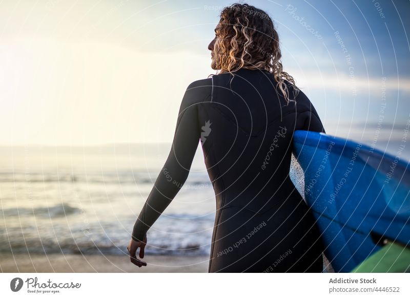 Frau steht am Ufer mit Surfbrett und schaut auf das Meer bei Sonnenuntergang Sonnenaufgang Neoprenanzug MEER Sportlerin Spaß nachdenken Wellen Brandung