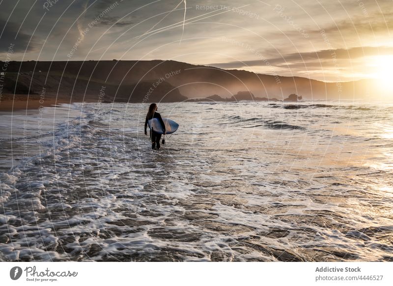 Frau mit Surfbrett steigt bei Sonnenuntergang ins Meer Sonnenaufgang Neoprenanzug MEER Sportlerin Spaß Silhouette Wellen Brandung Sonnenschein Urlaub Surfer
