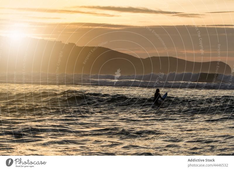Frau beim Surfen im Meer bei Sonnenuntergang Sonnenaufgang Neoprenanzug MEER Surfbrett Sportlerin Spaß Silhouette Wellen Brandung Sonnenschein Urlaub Surfer