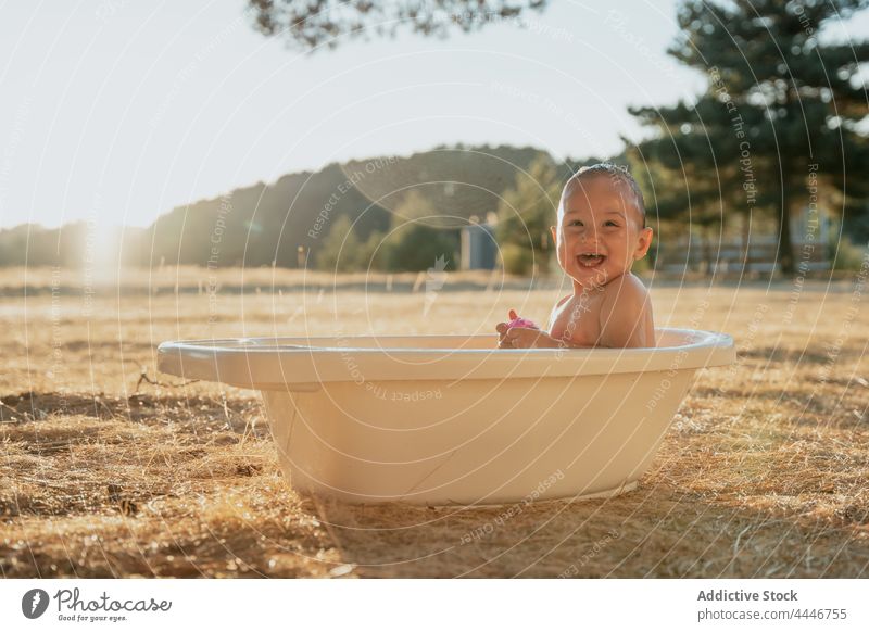 Fröhliches Baby hat Spaß in der kleinen Badewanne spielen Spaß haben heiter sorgenfrei Spielzeug Tropfen Landschaft unschuldig Kind Kleinkind froh