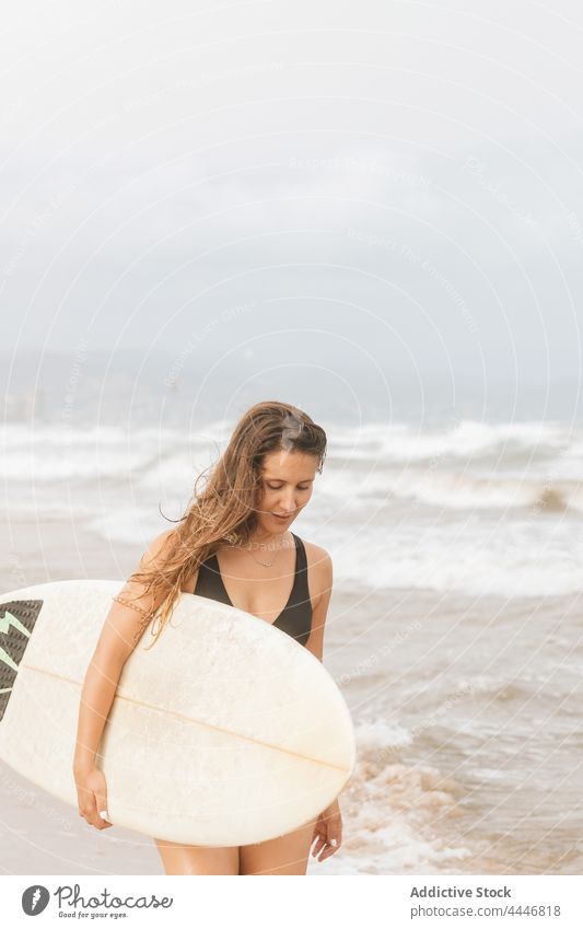 Surfer mit Surfbrett auf dem Kopf am Meeresstrand fliegendes Haar Sport Körper Badebekleidung Surfen genießen Frau Meeresufer Himmel nachdenklich Badeanzug