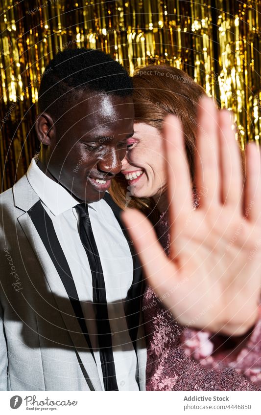 Lächelnde Frau zeigt auf einer Party eine Stopp-Geste gegen ihren schwarzen Freund Paar stoppen Kontrolle Partnerschaft privat Neujahr Vorabend Tierhaut feiern