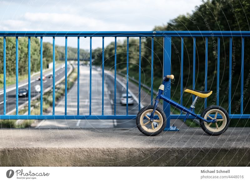 Altes Laufrad auf einer Brücke über der Autobahn Kind Kindheit Außenaufnahme Bewegung Kleinkind Fahrrad Spielen verflossen vergangen überblicken Sehnsucht