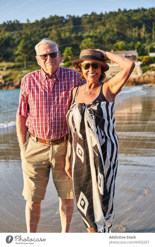 Älteres Paar am Strand stehend mit wogendem Meer Senior positiv MEER Sand Liebe Natur Ehefrau Ehemann Meeresküste Lächeln Zusammensein Partnerschaft Küste
