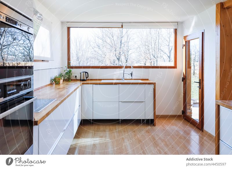 Ecke einer stilvollen Küche mit weißen und gemauerten Wänden, Holzboden und Arbeitsplatten aus Holz Grundbesitz Waschbecken Hocker Geräte Kabinett bequem