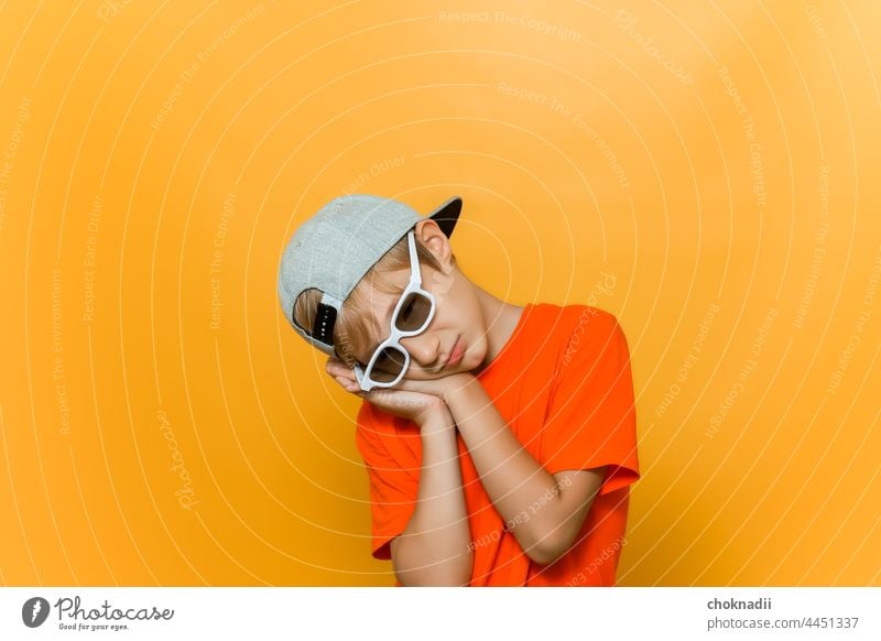 ein Kind mit einer Mütze und einer Brille, um Filme zu sehen, hat die Hände vor dem Kopf gefaltet und schläft Junge Sonnenbrille Mode Gesicht Person Menschen