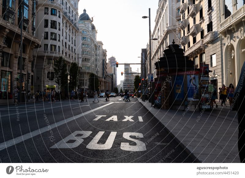 Ansicht der Gran Via im Zentrum von Madrid in der Morgendämmerung, im Vordergrund der Bus und die Taxispuren. Spanien September 5. Menschen laufen Sonnenlicht