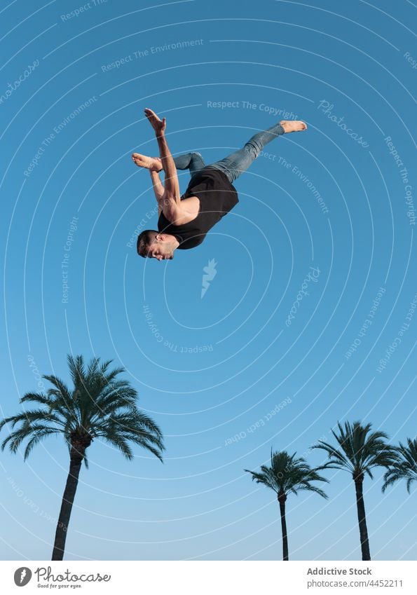 Energetische Tänzerin führt Kunststück in der Luft über Palmen Backend springen Trick extrem Energie Mut Adrenalin Blauer Himmel Mann dynamisch furchtlos Natur