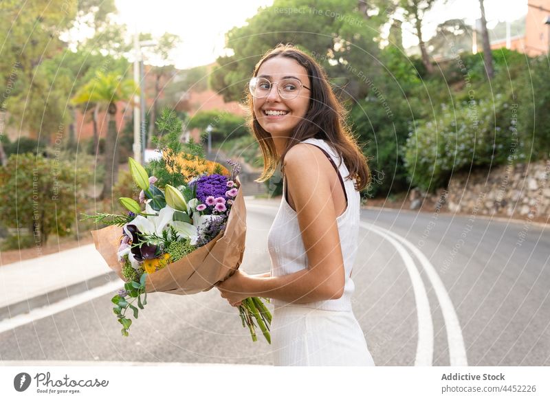 Glückliche Frau mit Blumenstrauß auf städtischer Straße Flora Lächeln romantisch freundlich Geschenk Blüte urban Überraschung Blütezeit heiter herzlich