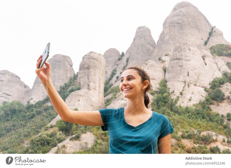 Lächelnde Frau nimmt Selfie auf Smartphone in felsiger Landschaft Tourist Berge u. Gebirge Ambitus positiv benutzend Hochland Ausflug Reisender Selbstportrait