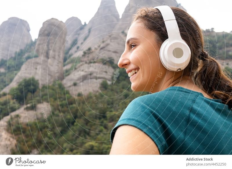 Achtsamer Reisender, der mit Kopfhörern vor einem Berg Musik hört zuhören Gesang meloman Berge u. Gebirge Frau benutzend Apparatur Gerät Reittier Urlaub