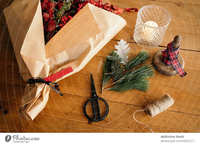 Stilvoller Blumenstrauß in der Nähe von Scheren und Bändern auf dem Holztisch Dekoration & Verzierung Weihnachten Papier umhüllen Handwerk dekorativ festlich