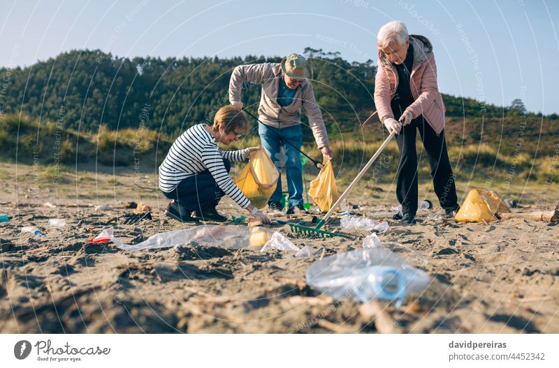 Freiwillige Senioren reinigen den Strand Menschengruppe Freiwilliger abholend Müll Reinigen Harke Aufnahmeclip geduckt dreckig Freiwilligenarbeit