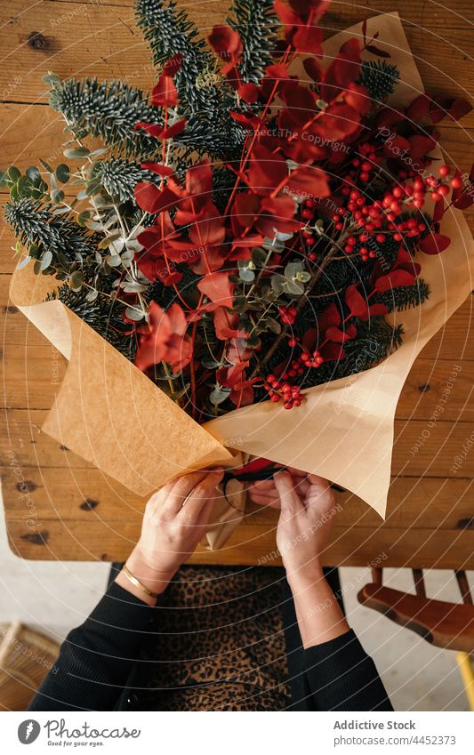 Floristin arrangiert Weihnachtsdekoration im Kreativstudio Frau Blumenhändler einrichten Blumenstrauß Weihnachten Dekor festlich Neujahr Eukalyptus