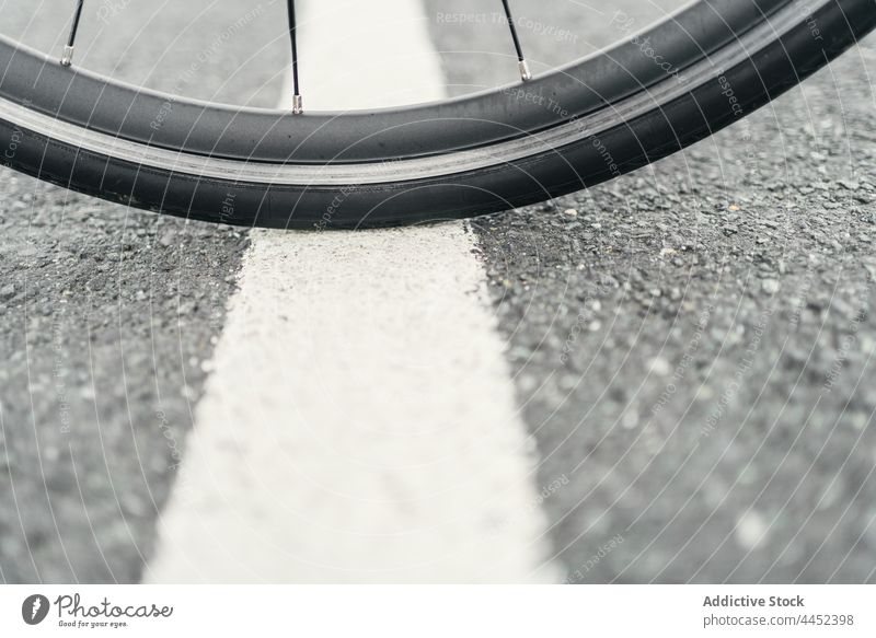 Fahrradrad auf asphaltierter Straße bei Tageslicht Rad Reifen Speiche Gummi Material Geometrie Symmetrie Asphalt Verkehr wellig Fahrbahn Fahrzeug Markierung